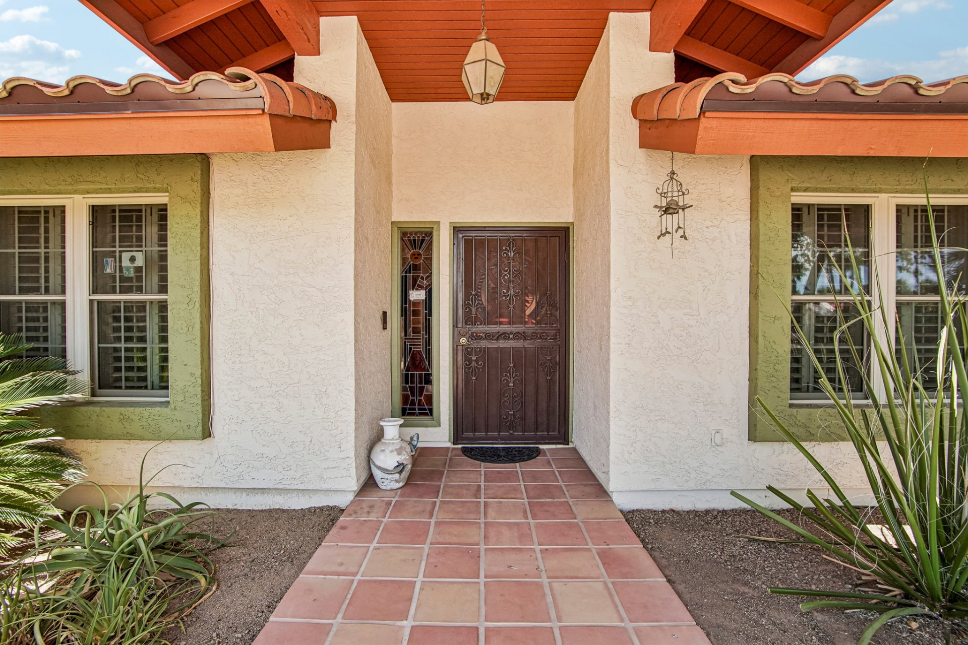 Front entrance with decorative iron door and terracotta tile walkway
